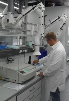 Ein Mann arbeitet in einem Labor. Über ihm ist ein Absaugarm angebracht.